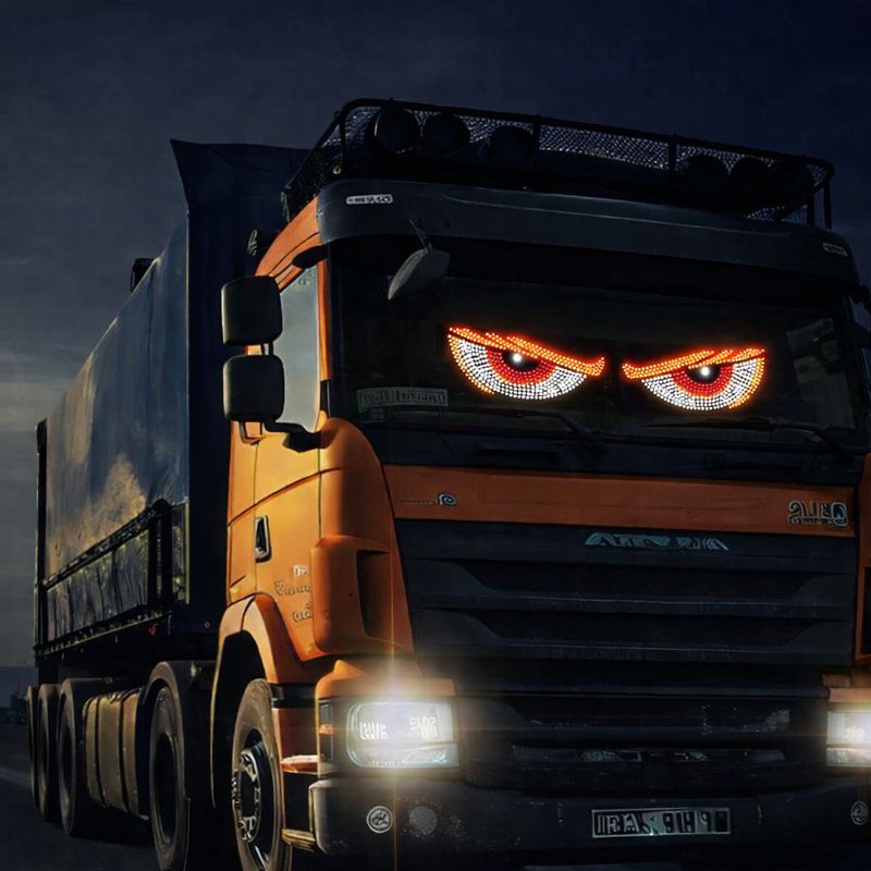 Orange truck with LED eyes display glowing in windscreen at night, custom vehicle lighting with red and white illuminated eye