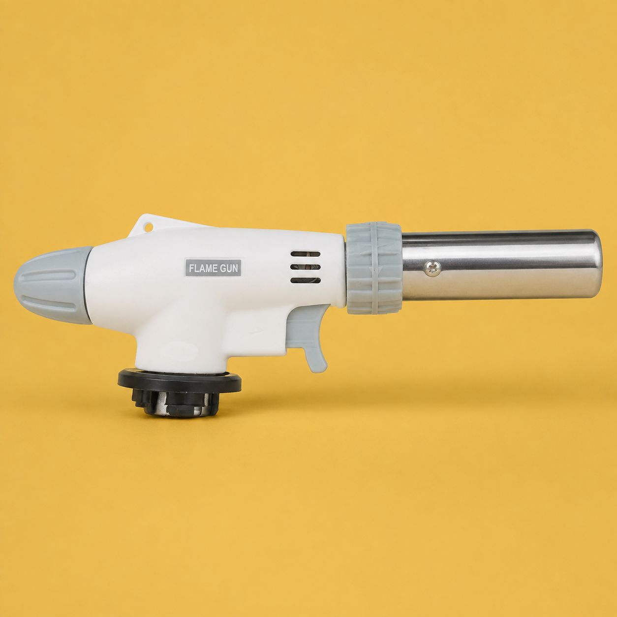 White butane gas torch attachment with grey controls, metal nozzle and black bayonet fitting on a golden-yellow background