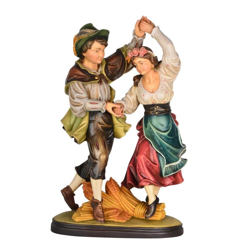 Fête des récoltes : homme et femme en costume traditionnel dansant, statues en bois