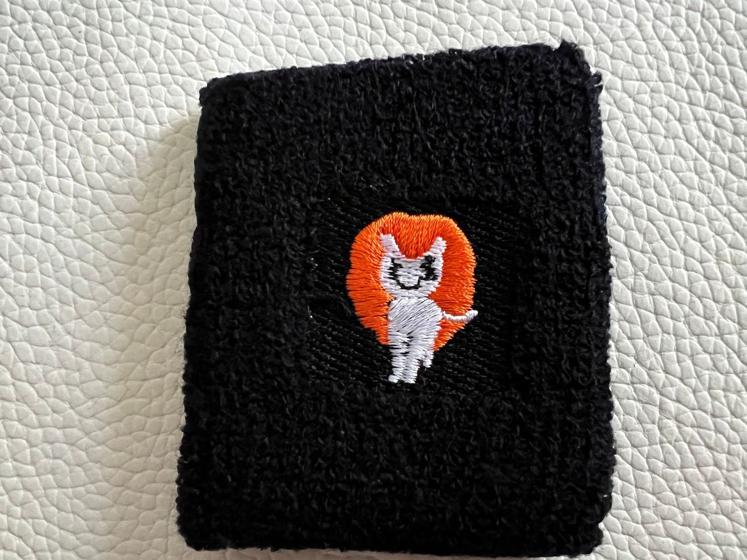 Handgelenk Schweißband - schwarz mit weiß/orangenem Pony