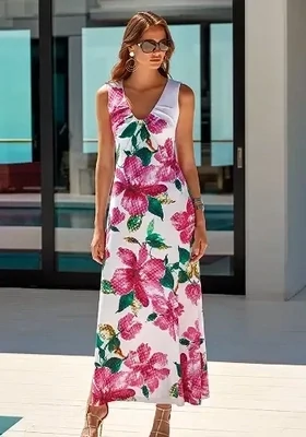Roidal Valeria Amina Column Dress. Modern print of up-scaled pink blooms with a little green foliage and the skirt has a side split. Lifestyle photo.
