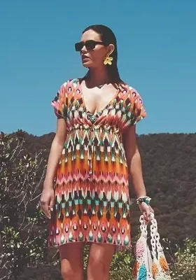 Ipanema Sundress Tunic by Nuria Ferrer. Featuring a v-neckline, this dress can be left loose or pulled in using the incorporated fabric ties. The fabric is a colourful ikat style pattern. Lifestyle photo.
