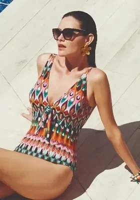 Ipanema Swimsuit by Nuria Ferrer. Colourful ikat style pattern fabric. A flattering plunge neckline with soft foam lined cups. The shoulder straps are adjustable to give a comfortable fit. Lifestyle photo.