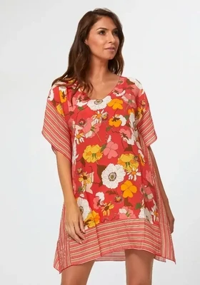 Lilia Sun Dress by Nuria Ferrer. The beach cover up has ½ sleeves for upper arm coverage and the hem falls just above the knees. The fabric is a stylised floral and stripe print on a red background. Front view.