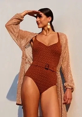 Siracusa Belted Swimsuit by Nuria Ferrer. The designer look woven fabric, in a copper tone has a herringbone overlay in a metallic copper thread. Lifestyle photo.