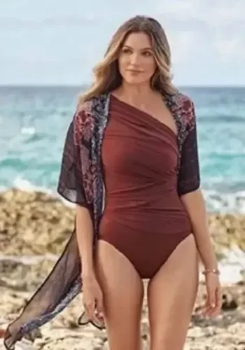 Miraclesuit Mendhika Beach Wrap Kimono. A flowing Kimono style cover-up featuring a stylised flower print in a 'tamarind' deep reddish brown, over an intricate black and white background. Lifestyle photo.