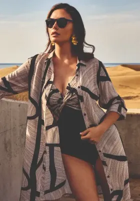 Lifestyle photo of the David Swimwear Irma Swimsuit in a black and mocha design with ruching over the bust with gold sparkles