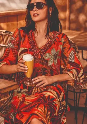 Lifestyle photo of David Swimwear Paradise Island Kim Kaftan, with a V neck, in a tropical print in warm spice colours. 