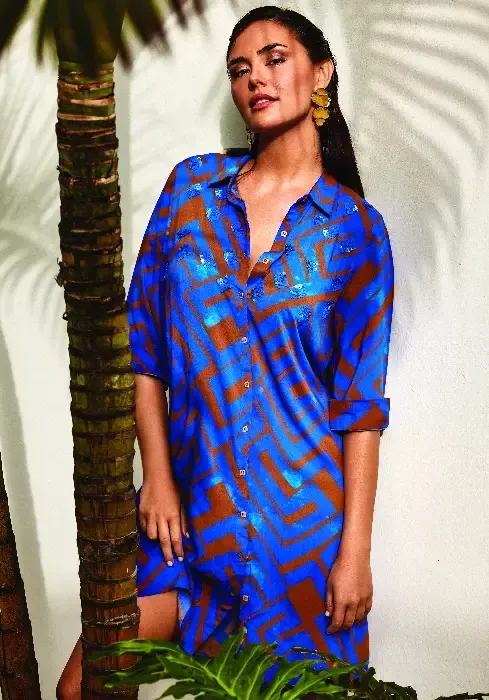Lifestyle of the David Swimwear Freedom shirt dress in a modern abstract  copper brown print on blue. Buttons to the front