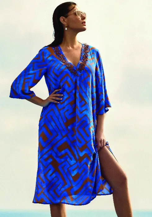 Lifestyle photo of the David Swimwear Kim Kaftan in a copper abstract print on a blue background