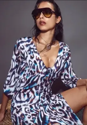 Alika Sun Dress by Nuria Ferrer. Featuring a peepo deep v-neckline with a small, slim black hoop which draws the Blue and White Animal print fabric together. Lifestyle photo.