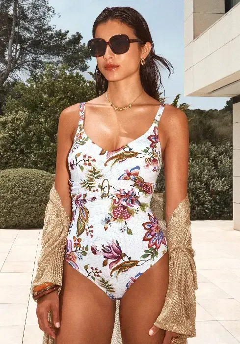 Jasmine Golden Loop Swimsuit by Nuria Ferrer. The fabric features a highly detailed print of beautiful flowers and butterflies and looks so realistic that you will want to touch it just to check whether it is real embroidery. Lifestyle photo.