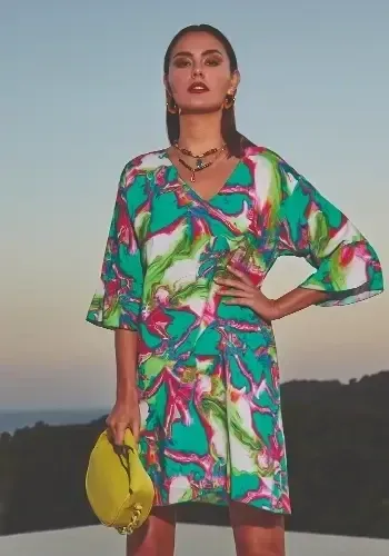 Frida Sundress Tunic by Nuria Ferrer, in a colourful emerald green and pink marbled print. Featuring a v-neckline and ¾ length sleeves the tunic hemline falls just above the knee. Lifestyle photo.