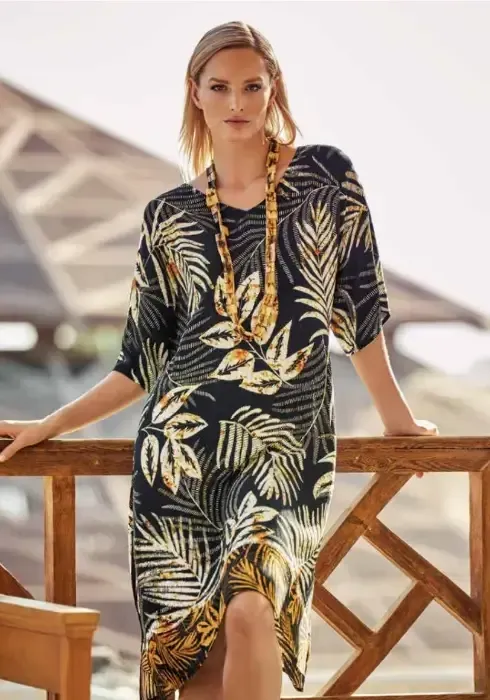 Seductive Leaves Tunic Dress by Charmline. The fabric features a stylised abstract foliage print in cream, with touches of a soft burnt orange, against a black background. Lifestyle photo.