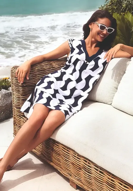 Lise Charmel Croisiere For Ever Shift Dress. Blue and White up & down graphic print. Decorative golden ring to front centre. Lifestyle photo.