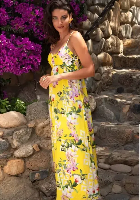 Lise Charmel Jardin Delice Maxi Dress. The fabric is a floral print on a yellow background. Lifestyle photo.