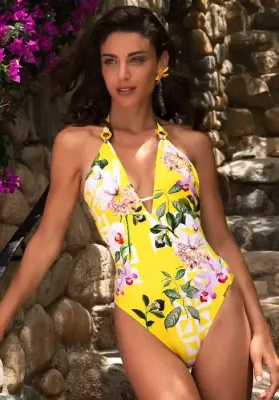 Lise Charmel Jardin Delice Swimsuit with deep V neckline in a floral print on  a yellow background. Lisestyle photo.