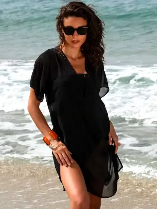 Lise Charmel Ajourage Couture Tunic Sundress. Lightweight tunic dress in black fabric with precisely cut lace effect band around the front and back necklines. Lifestyle photo.