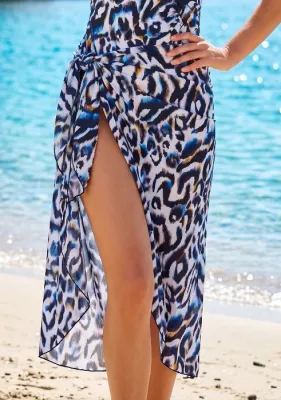 Alika PAREO by Nuria Ferrer Close up of a model wearing a Nuria Ferrer Alika pareo. The fabric is a white, blue and black animal print with orange flecks