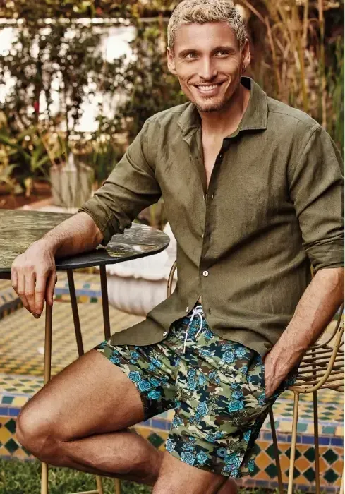 Lifestyle photo of Atlantis Camo Romance Swim Shorts. Blue roses on a green camouflage background.