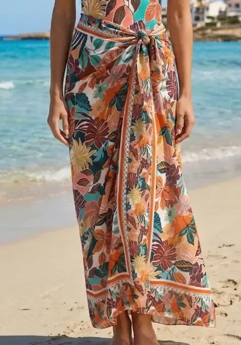 A model wears a multicoloured Nurai Ferrer Sorella sarong on a sandy beach