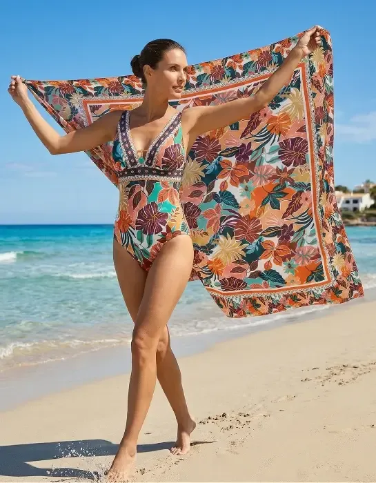 A model wears a multicoloured Nurai Ferrer Sorella sarong on a sandy beach