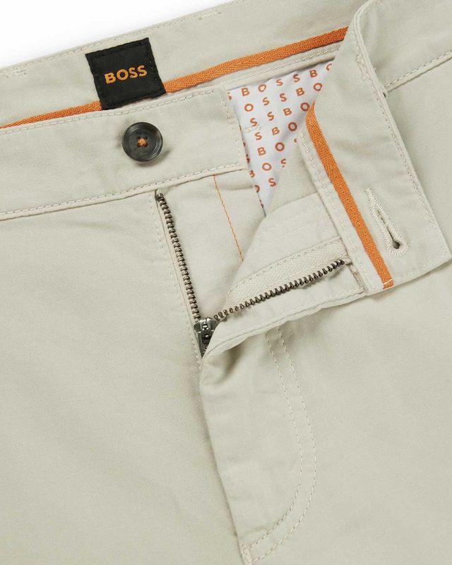 Detail van gulp en binnenzijde van beige Hugo Boss chino met oranje accenten