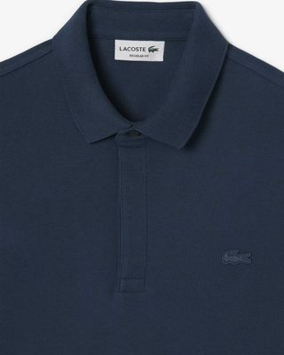Detail van de Lacoste Paris polo in azuurblauw met ton-sur-ton logo en verborgen sluiting

