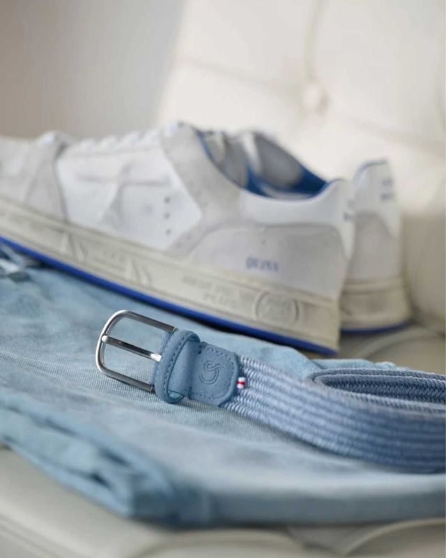Detailopname van de Sicilia riem bij lichte outfit en sneakers

