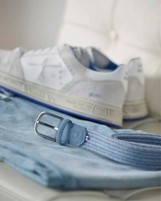 Detailopname van de Sicilia riem bij lichte outfit en sneakers

