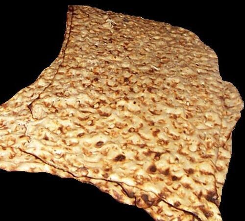 Sangak bread on a rustic wooden surface, showcasing its distinct oval shape, crispy golden-brown crust, and textured surface dotted with irregular air pockets, typical of this traditional Persian flatbread.