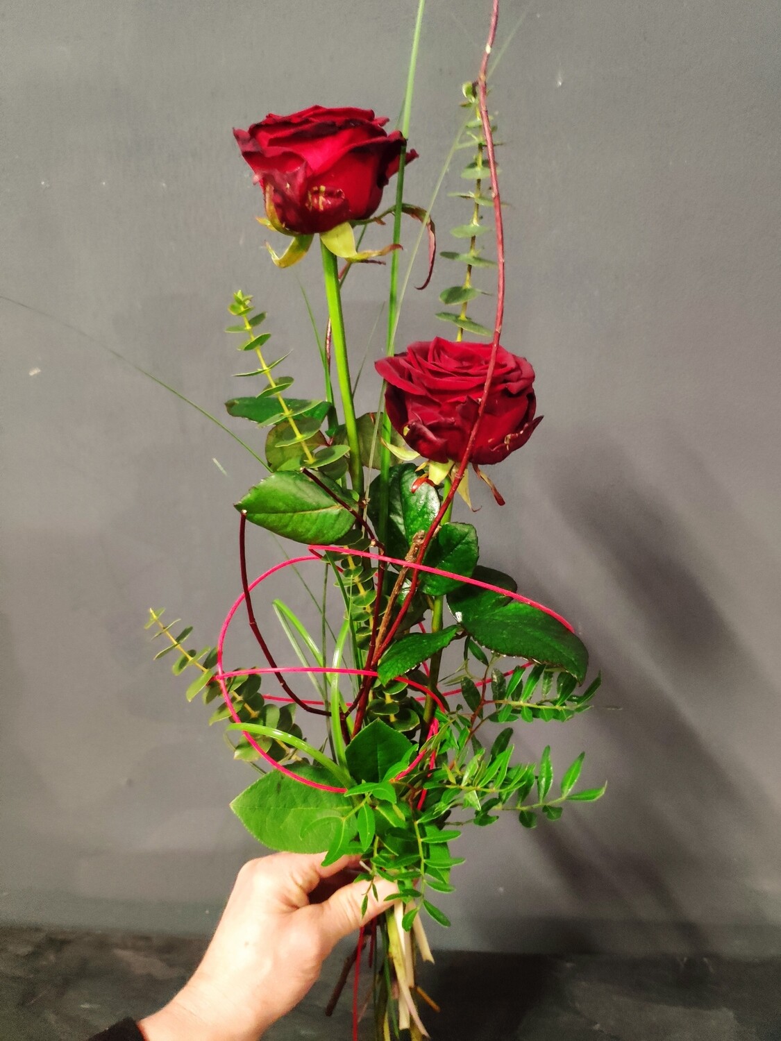 Zwei langstielige rote Rosen mit Grün