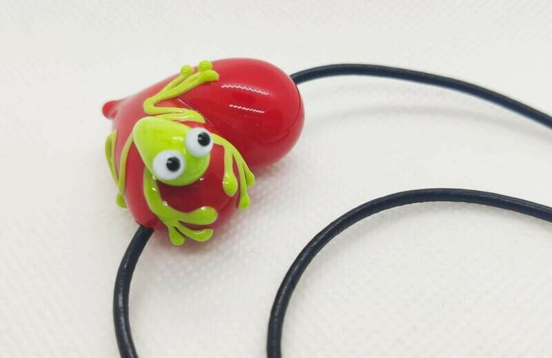 Frosch-Herz. Rotes Herz aus Glas mit zuckersüßem Frosch an kurzem Lederband