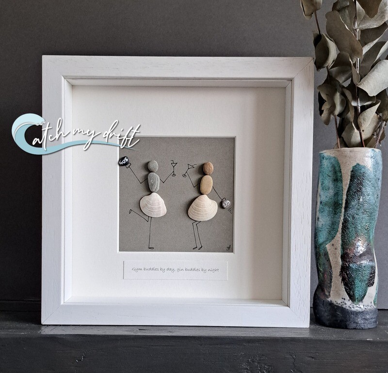 2 girls made with beach pebbles &amp; shells, each holding a kettlebell whilst having a drink with the quote Gym buddies by day, gin buddies by night