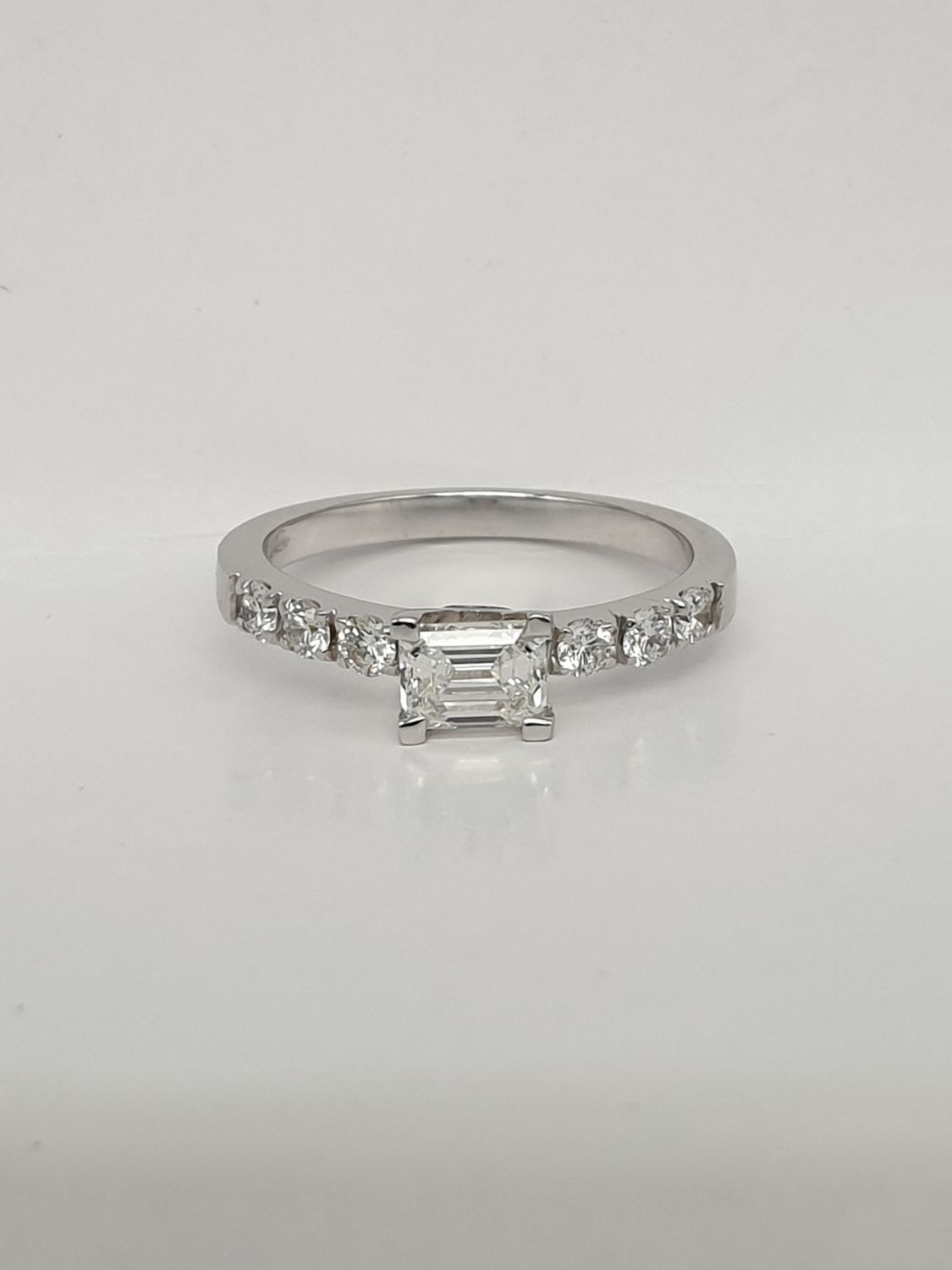 Anello in oro bianco con Diamante taglio smeraldo ct. 0,61 e sei diamanti laterali ct. 0,30
