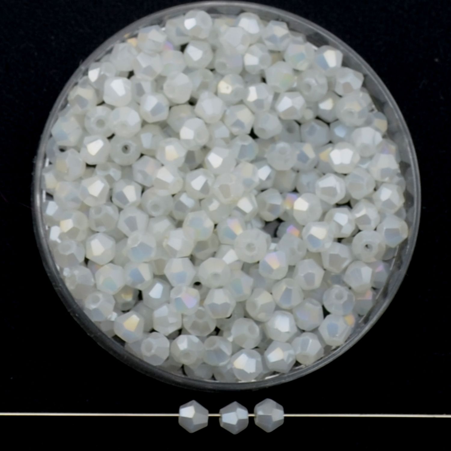 Facettierte Glasperlen in Kristallweiß, Bicone-Schliff, 3 mm, mit AB-Schimmer auf schwarzem Hintergrund