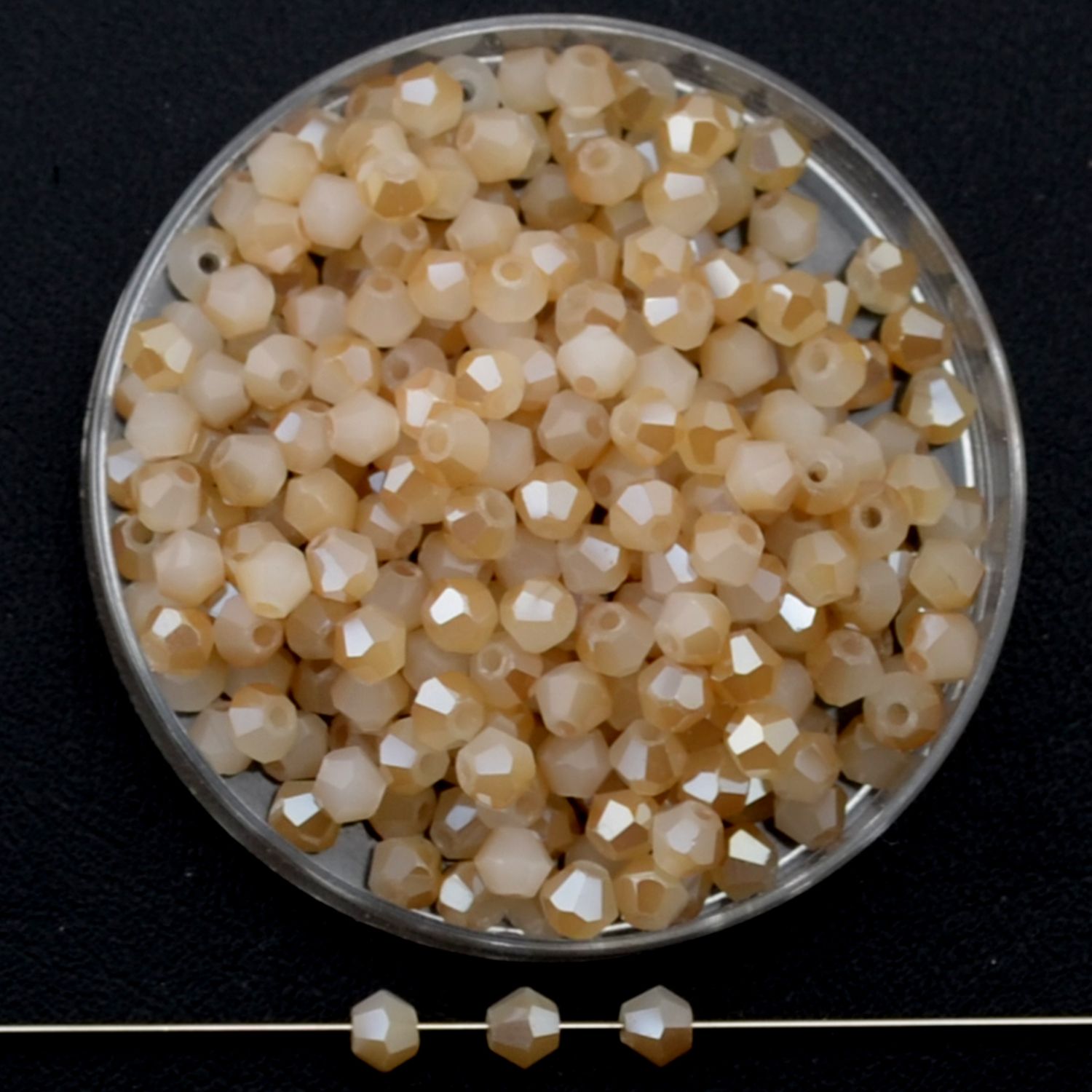 Facettierte Glasperlen in Karamellbeige, Bicone-Schliff, 3 mm, glänzend auf schwarzem Hintergrund