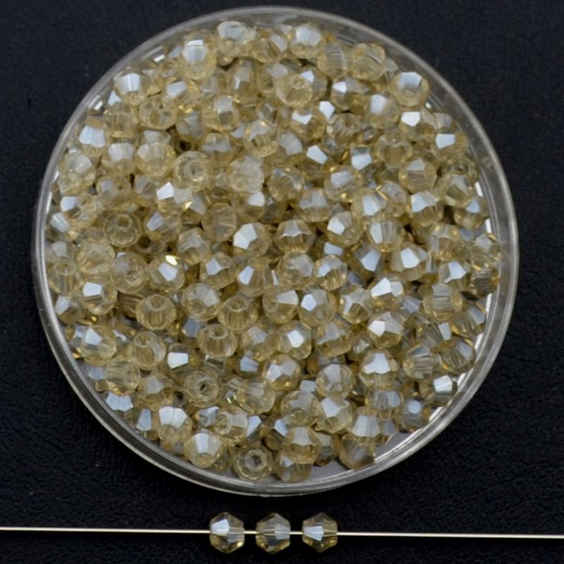 Doppelkegel-Kristallglasperlen – Champagnerkristall AB-Effekt, 3 mm I 40 Stück Facettierte Glasperlen in Champagner, Bicone-Schliff, 3 mm, mit AB-Schimmer auf schwarzem Hintergrund
