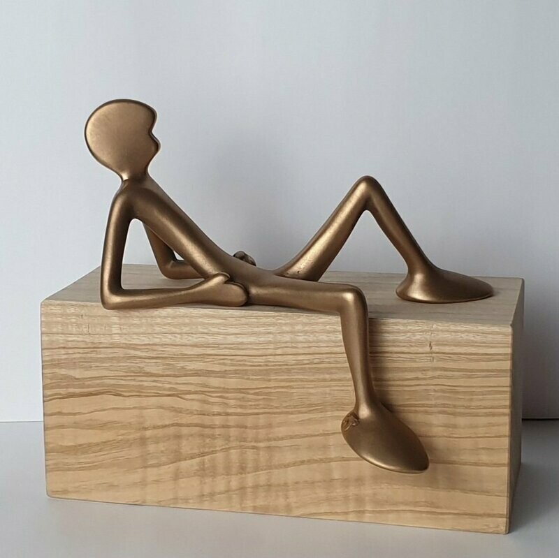 Das Bild zeigt  die Bronzeskulptur "Kleiner liegender Friend mit Eschenholzsockel" von Bildhauer Oliver Pohl aus Haste.