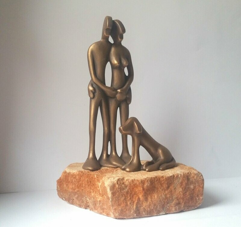 Das Bild zeigt die Bronzefiguren Friendspaar und Friendshund auf einem roten Stein montiert, Titel "Absolute Hundeliebe".