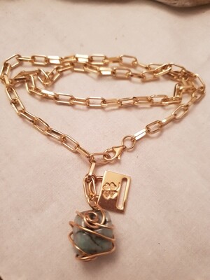 Collana regolabile in alluminio dorato ed acciaio con ciondolo in smeraldo incastonato.