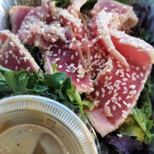 sesame seed crusted seared tuna atop mixed greens
