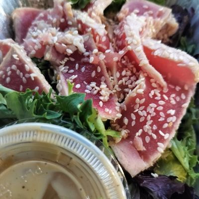 sesame seed crusted seared tuna atop mixed greens