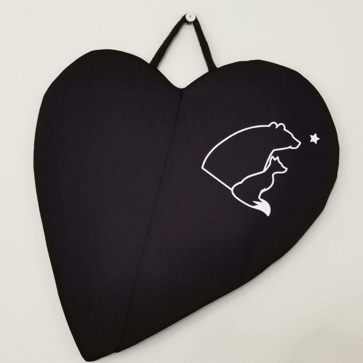 Musta taskullinen patalappu, joka suojaa &quot;pellin alapuolisia&quot; sormia palovahingoilta.