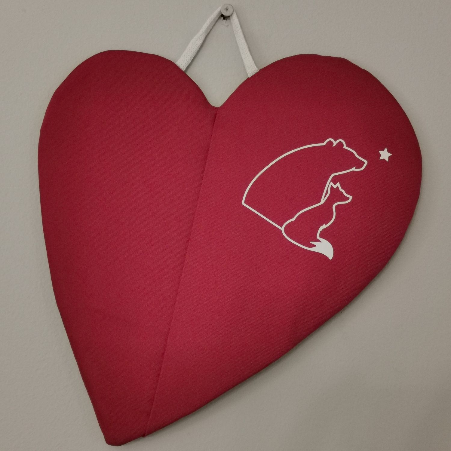 Punainen taskullinen patalappu, joka suojaa &quot;pellin alapuolisia&quot; sormia palovahingoilta.