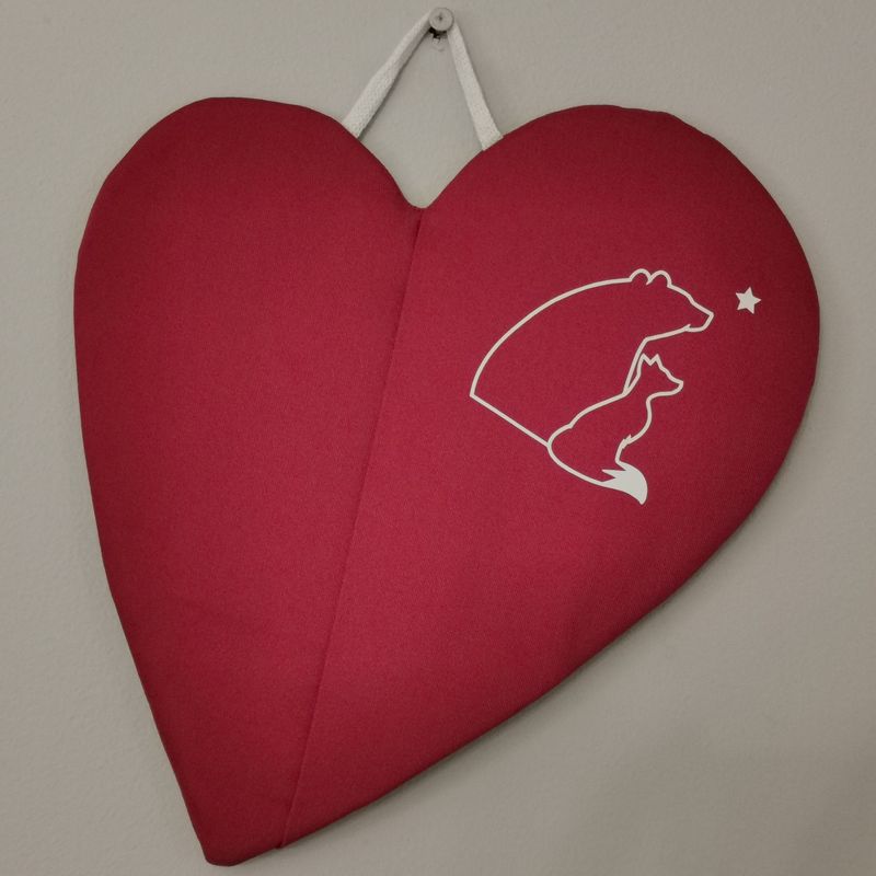 Punainen taskullinen patalappu, joka suojaa &quot;pellin alapuolisia&quot; sormia palovahingoilta.