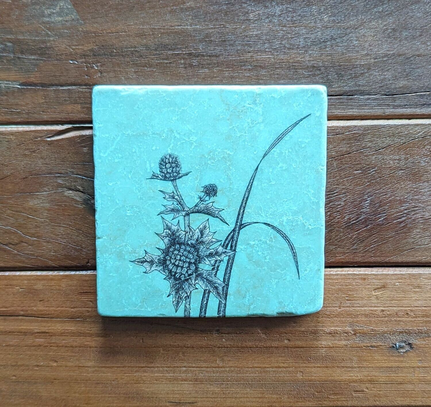 Dekofliese/Untersetzer Distel auf eisblauem Hintergrund, Keramik; Künstlerarbeit, Zeichnungen werden mit einer Drucktechnik auf die Fliese aufgebracht; 10 x 10cm