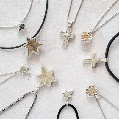 Gruppenbild verschiedener Schmuckstücke mit Tierhaaren in Form von großen und kleinen asymetrischen Sternen und Kreuze
