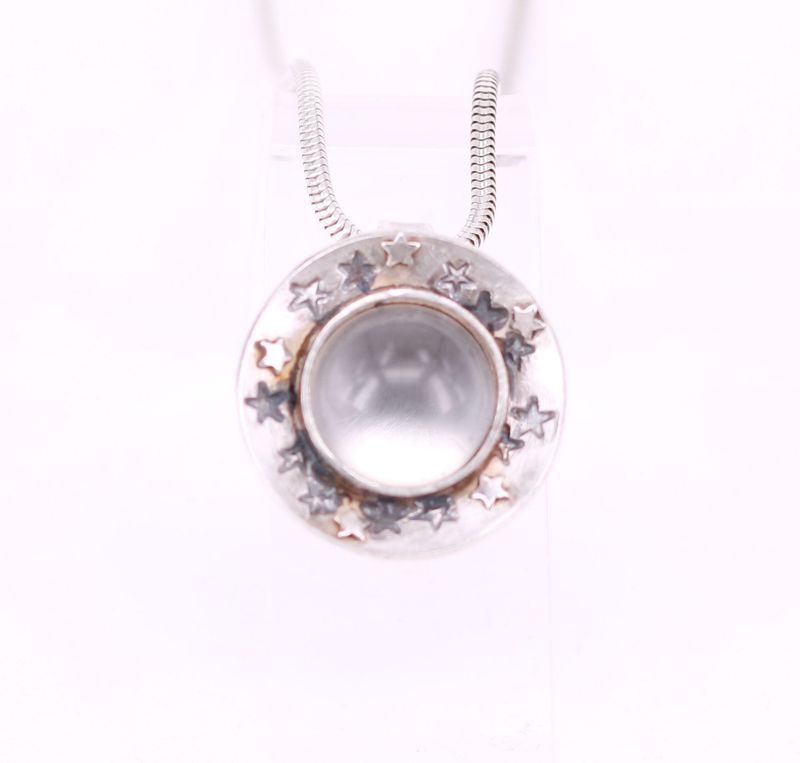 Tierhaare unter rundem Bergkristall gefasst mit Sternenschale