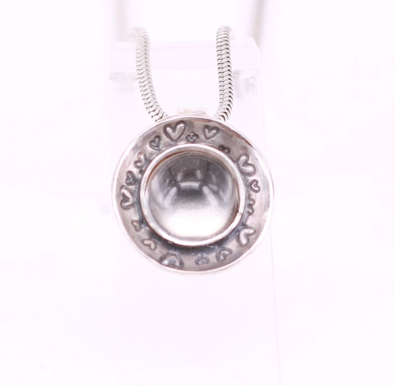 Tierhaare unter rundem Bergkristall mit Herzschale